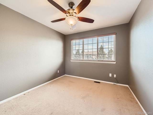 carpeted empty room featuring visible vents, ceiling fan, and baseboards