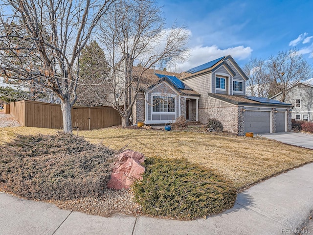 view of front of property with brick siding, fence, solar panels, and concrete driveway