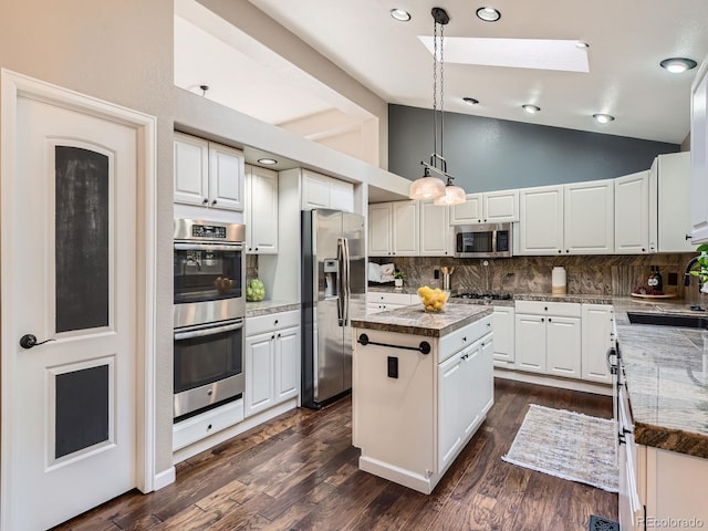 kitchen featuring lofted ceiling with skylight, a kitchen island, stainless steel appliances, and a sink