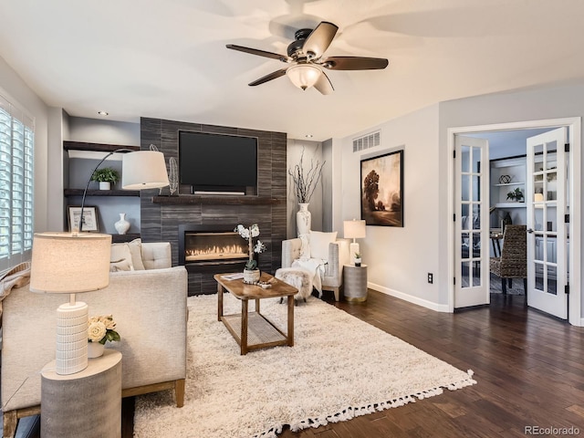 living area with baseboards, visible vents, a ceiling fan, wood finished floors, and a fireplace