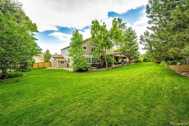 view of yard with a storage shed, a patio area, fence, and an outdoor structure