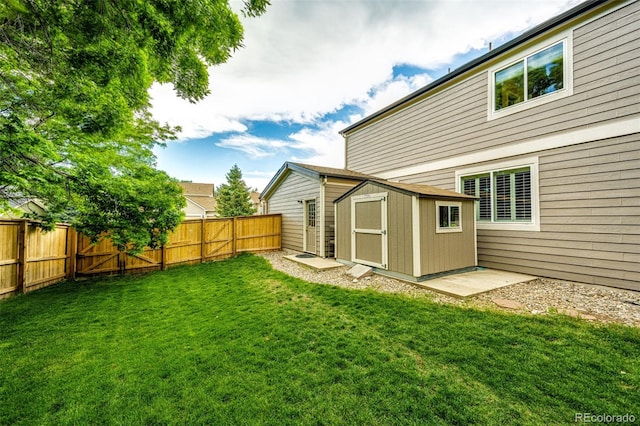 view of yard with a fenced backyard, an outdoor structure, and a storage unit