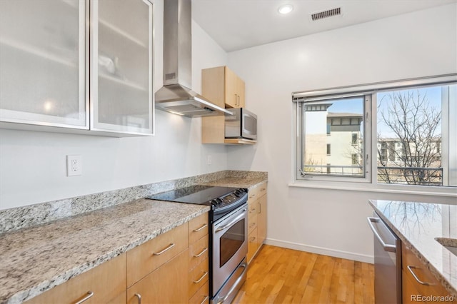 2958 Syracuse St Unit 316, Denver, CO 80238 - kitchen with stainless steel appliances, wall chimney exhaust hood, light wood-style flooring, baseboards, and light stone countertops