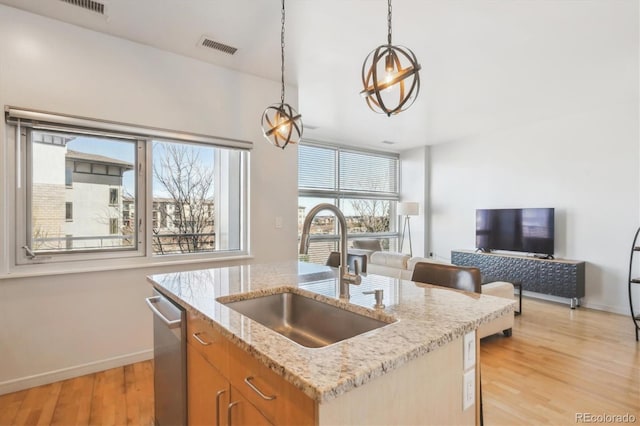 2958 Syracuse St Unit 316, Denver, CO 80238 - kitchen featuring a sink, baseboards, light wood-type flooring, open floor plan, and decorative light fixtures