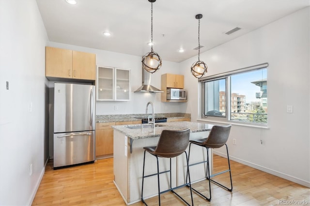 2958 Syracuse St Unit 316, Denver, CO 80238 - kitchen featuring freestanding refrigerator, wall chimney range hood, a center island with sink, light wood-style floors, and recessed lighting
