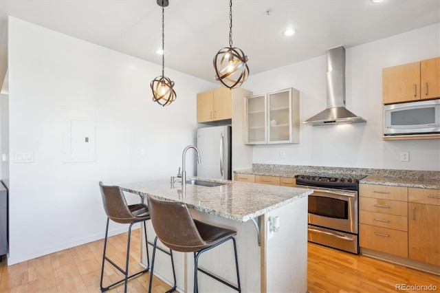 2958 Syracuse St Unit 316, Denver, CO 80238 - kitchen featuring appliances with stainless steel finishes, wall chimney range hood, a sink, light wood-style flooring, and a breakfast bar area