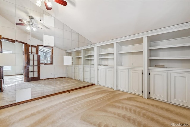 carpeted empty room with a ceiling fan, vaulted ceiling, and built in features