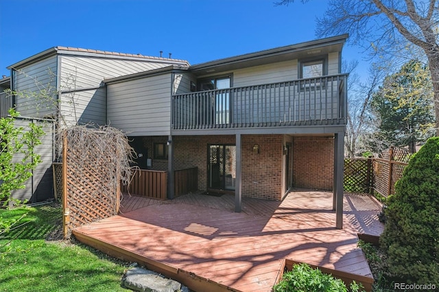 back of house with a balcony, a deck, and brick siding
