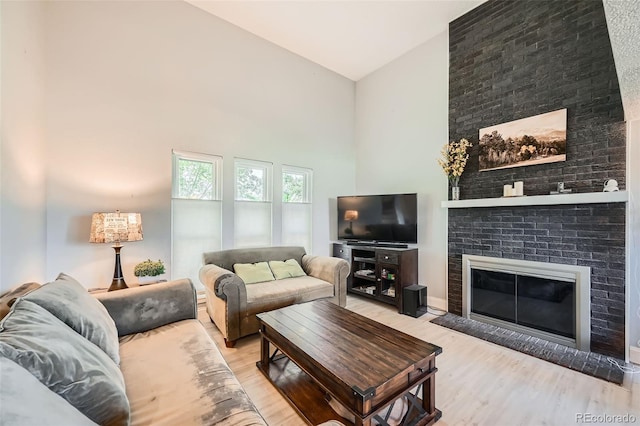 living room featuring high vaulted ceiling, wood finished floors, and a brick fireplace