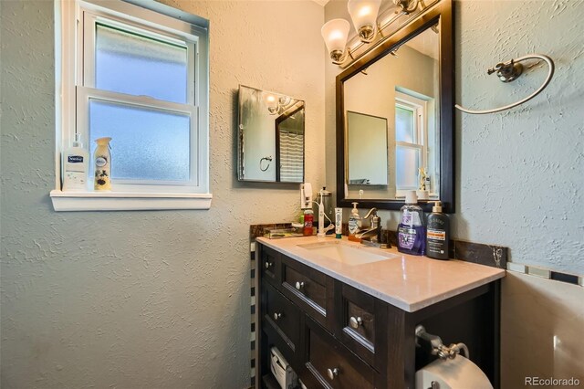 bathroom featuring healthy amount of natural light, vanity, and a textured wall
