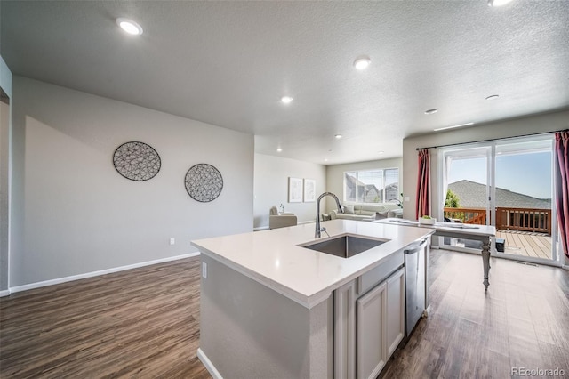 17028 Osage St, Broomfield, CO 80023 - kitchen with dark wood-style flooring, stainless steel dishwasher, open floor plan, light countertops, and a center island with sink