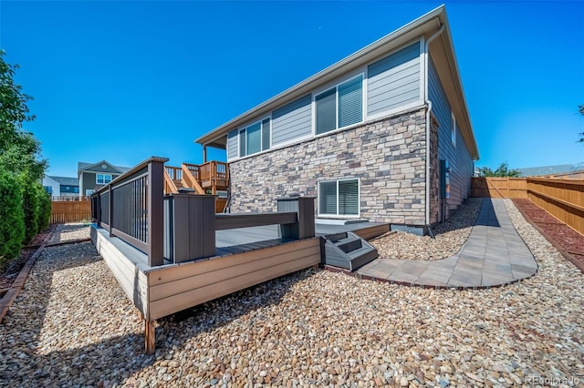 17028 Osage St, Broomfield, CO 80023 - rear view of property with a fenced backyard, stone siding, and a deck