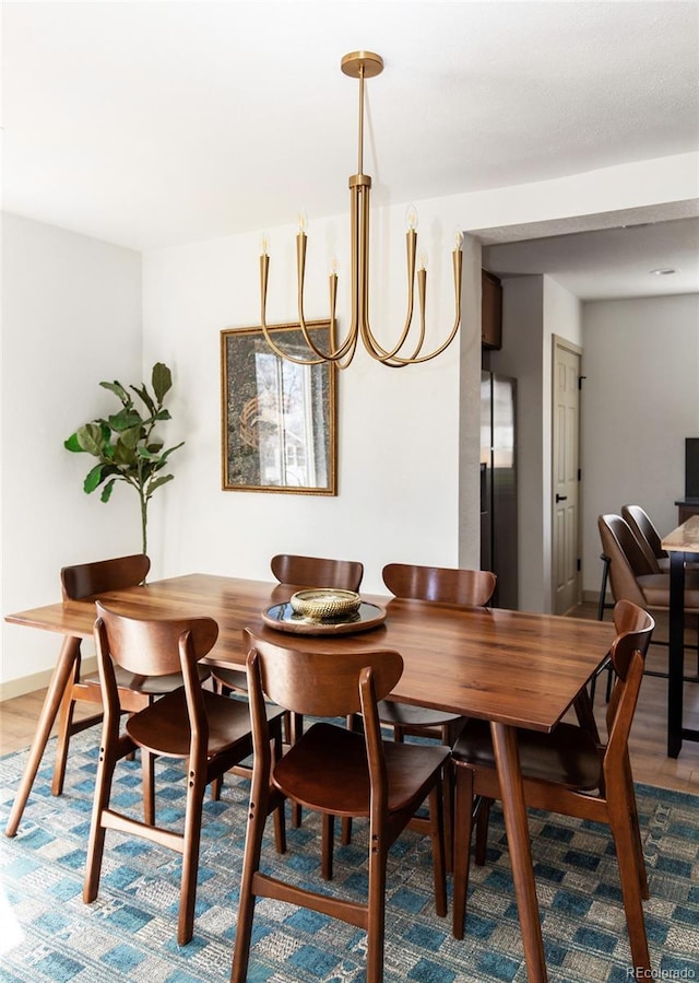 dining space featuring a chandelier, baseboards, and wood finished floors