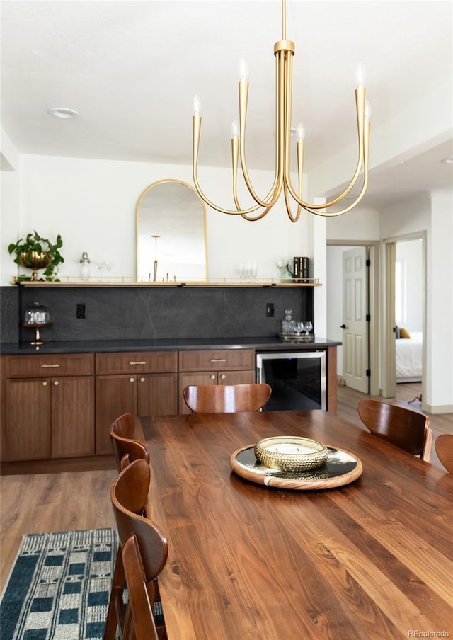 dining space featuring beverage cooler, a bar, and wood finished floors