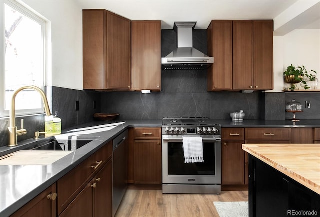 kitchen featuring a sink, wall chimney exhaust hood, plenty of natural light, and stainless steel appliances