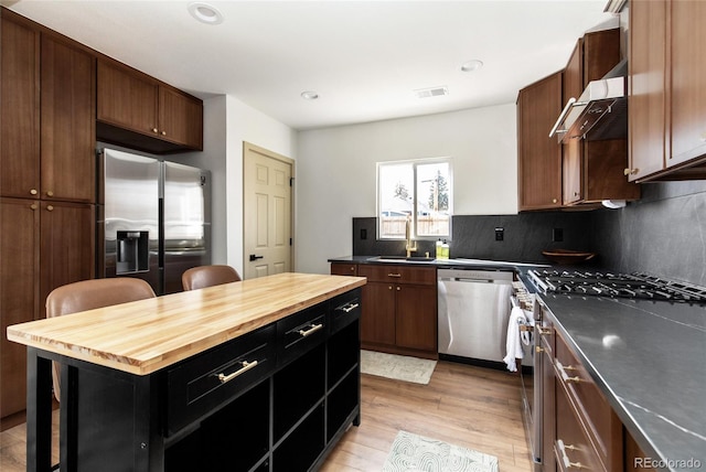 kitchen featuring visible vents, a sink, appliances with stainless steel finishes, wood counters, and backsplash