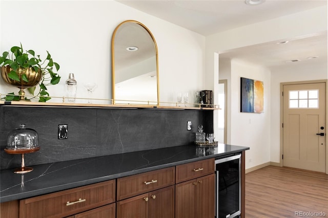 kitchen featuring dark countertops, beverage cooler, tasteful backsplash, and light wood-type flooring