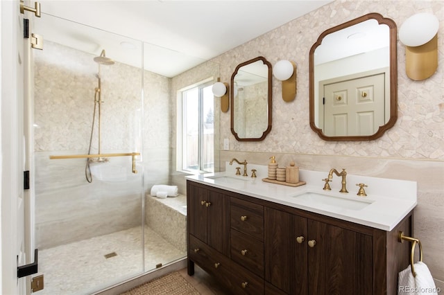 bathroom with a sink, double vanity, a shower stall, and wallpapered walls