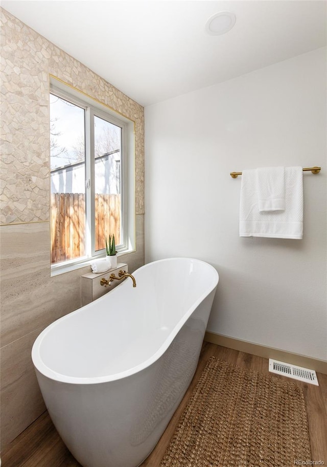 full bathroom with a soaking tub, wood finished floors, and visible vents