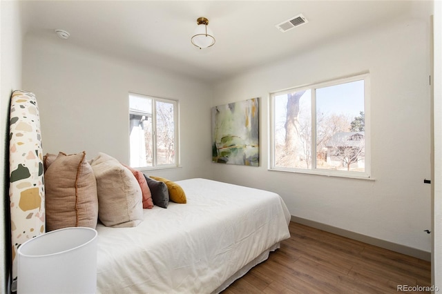 bedroom featuring visible vents, baseboards, and wood finished floors