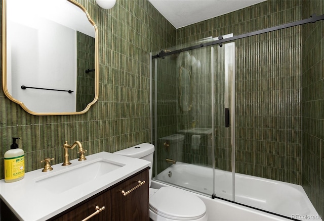 full bathroom featuring vanity, tile walls, toilet, and bath / shower combo with glass door