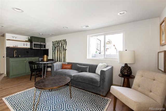 living room with recessed lighting, visible vents, and light wood finished floors