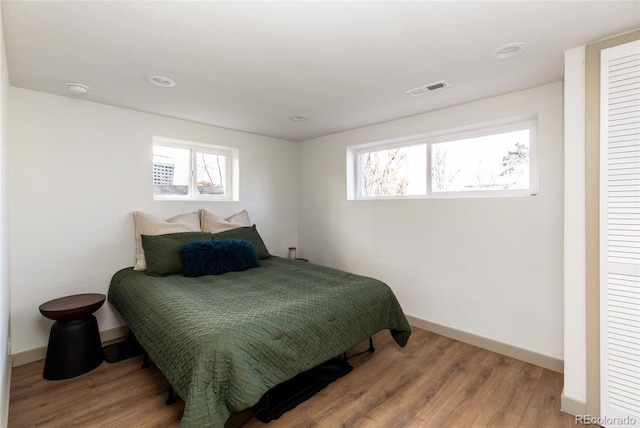 bedroom with visible vents, multiple windows, baseboards, and wood finished floors