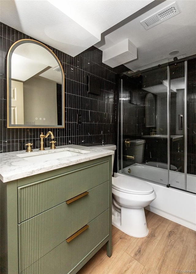 bathroom featuring visible vents, toilet, tile walls, and wood finished floors