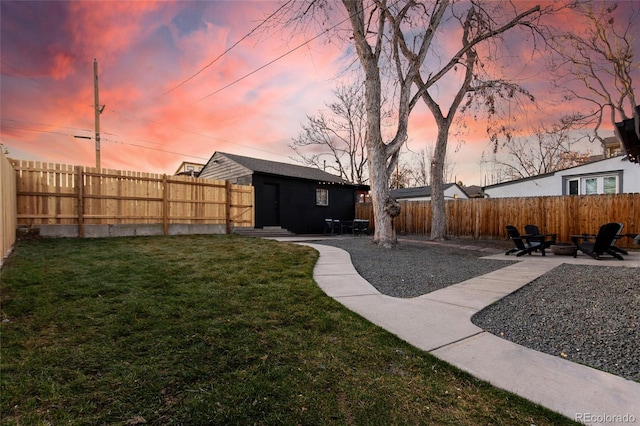 yard at dusk featuring an outbuilding, a fenced backyard, and a patio