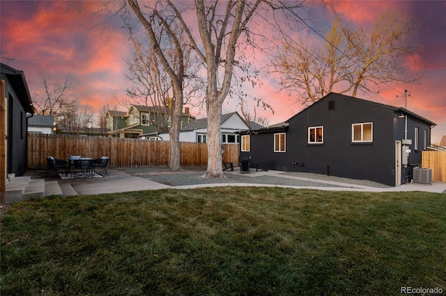 back of property at dusk featuring a patio area, a yard, and fence