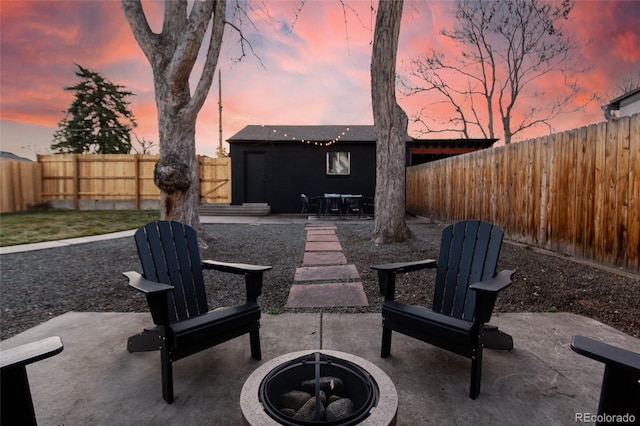 patio terrace at dusk with an outbuilding and a fenced backyard