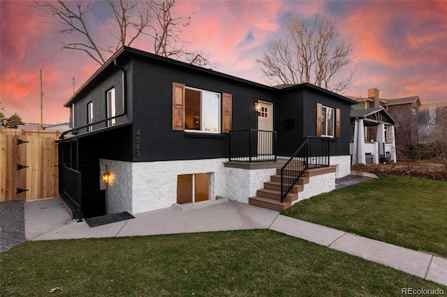 view of front of home featuring a yard, fence, a patio area, and stucco siding