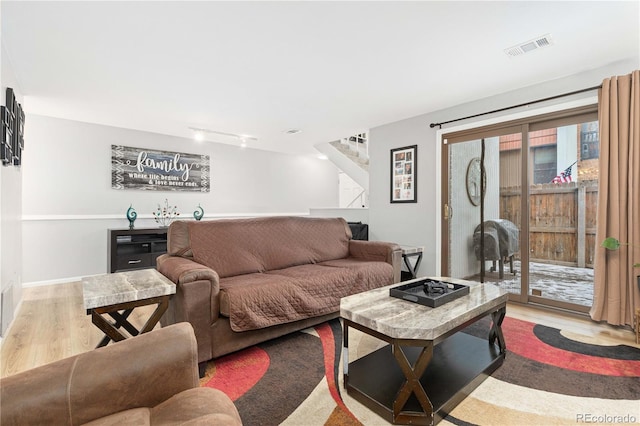 living room with light wood-style floors, rail lighting, visible vents, and baseboards