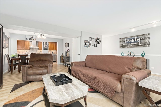 living area with light wood-type flooring, rail lighting, and baseboards