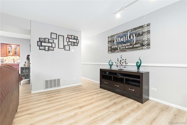 bar with baseboards, visible vents, rail lighting, light wood-style floors, and backsplash