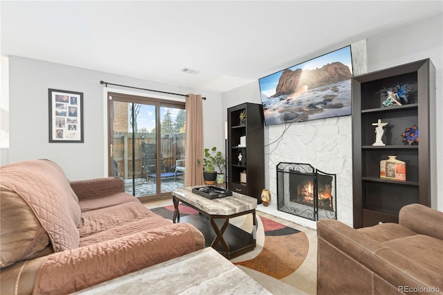 living room featuring a stone fireplace and built in shelves