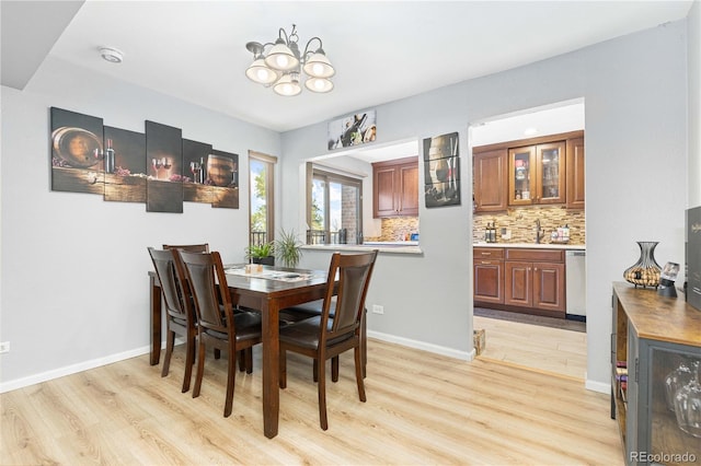 dining space featuring light wood finished floors, baseboards, indoor wet bar, and a notable chandelier