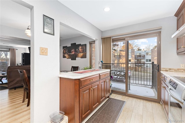 kitchen with brown cabinets, light wood-style floors, light countertops, and decorative light fixtures