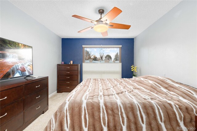 bedroom featuring a textured ceiling, baseboards, a ceiling fan, and light colored carpet