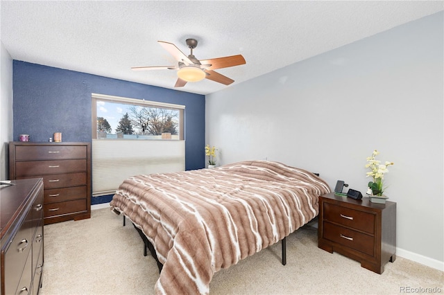 bedroom featuring a textured ceiling, ceiling fan, baseboards, and light colored carpet