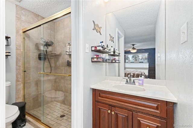 ensuite bathroom with a textured ceiling, ceiling fan, connected bathroom, toilet, and a stall shower