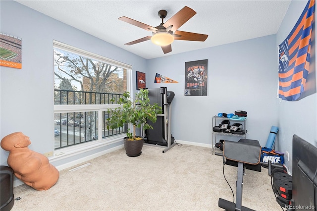 workout area with visible vents, light colored carpet, ceiling fan, a textured ceiling, and baseboards