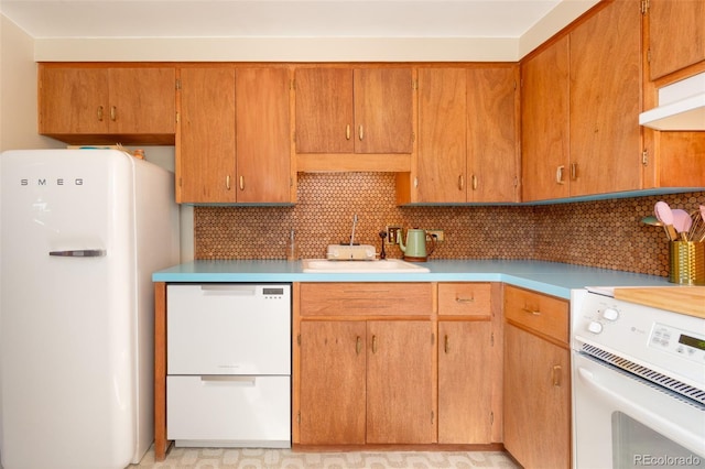 kitchen featuring a sink, decorative backsplash, white appliances, and light countertops