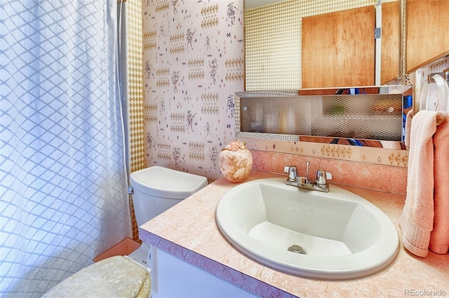 bathroom with vanity, wallpapered walls, and toilet