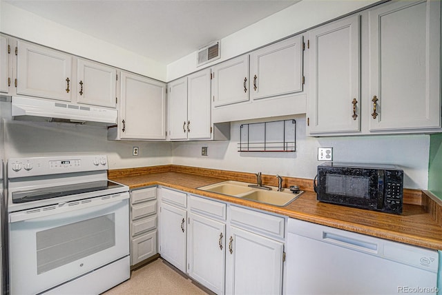 kitchen featuring visible vents, a sink, under cabinet range hood, and white appliances