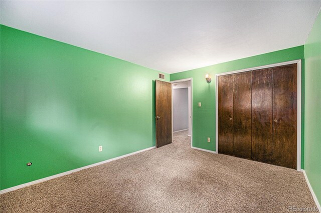 unfurnished bedroom featuring carpet floors, baseboards, visible vents, and a closet