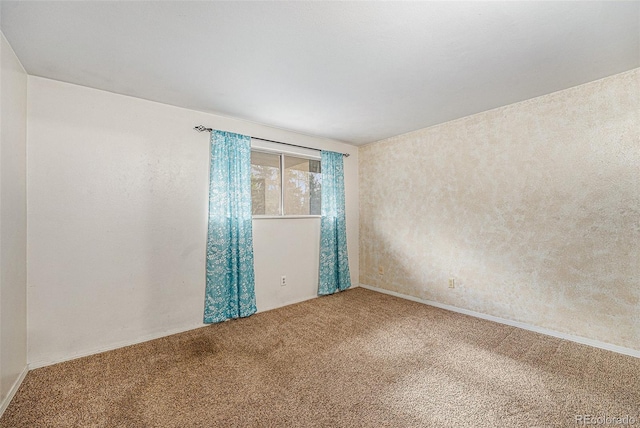 spare room featuring carpet floors and baseboards