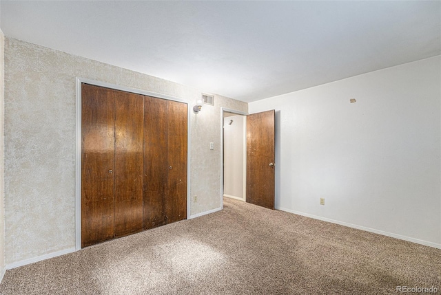 unfurnished bedroom with carpet floors, baseboards, visible vents, and a closet