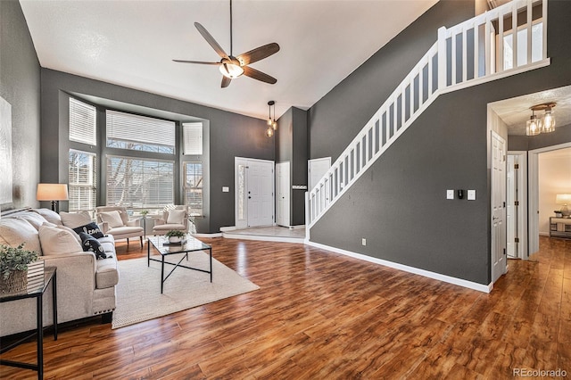 living room with ceiling fan, a towering ceiling, and hardwood / wood-style flooring