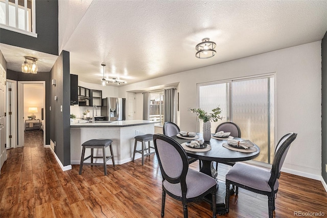 dining room with a textured ceiling and dark hardwood / wood-style flooring